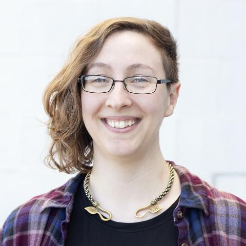 Elizabeth, wearing a gold laurel necklace and plaid, smiles.