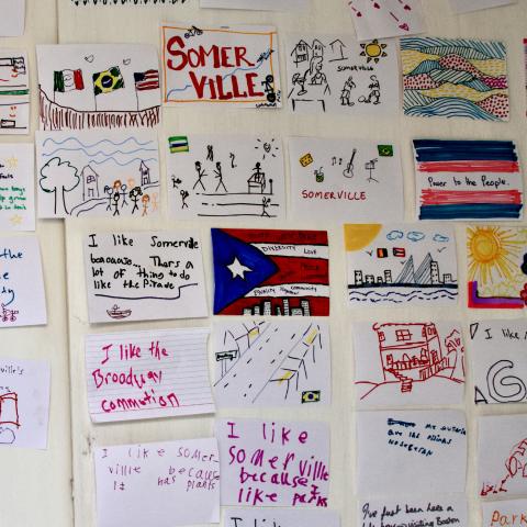 A wall with a collection of hand drawn illustrations on 8.5x11 paper sheets.