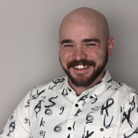 Man with white button down shirt sitting near a wall