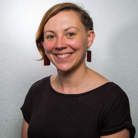 A woman with bobbed hair wearing a black top and rectangular earrings