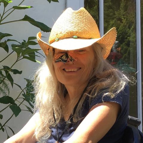 Judith wears a cowboy hat as a monarch butterfly rests on her nose.