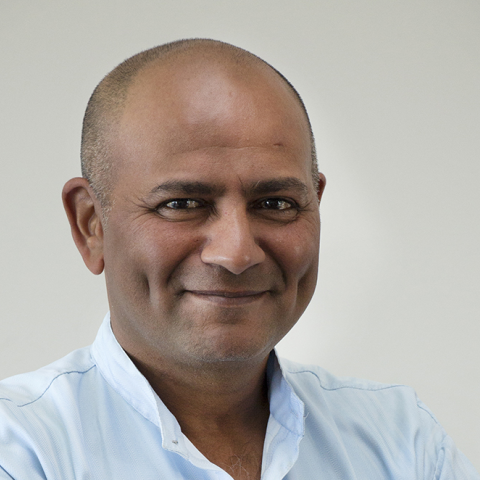 a headshot of a man with brown skin wearing a light blue collared shirt