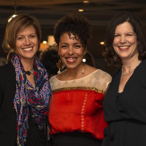 Three women pose smiling at the camera.