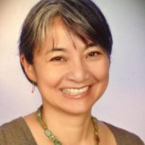 A woman in a green top and bead necklace smiling