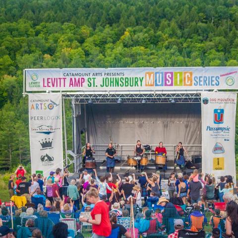 Outdoor festival stage with large crowd of people on grass