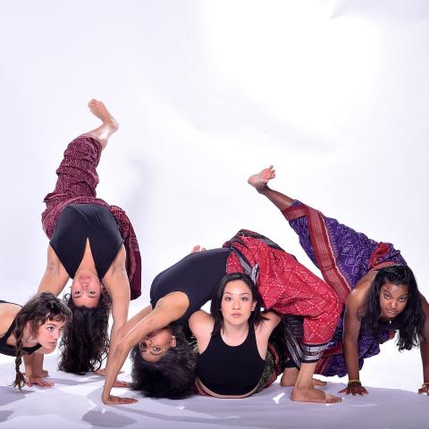 Five women dance in yoga pants along the floor
