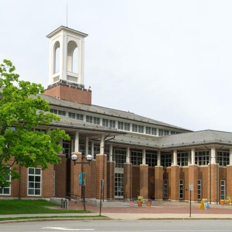 On a sunny day, a brick building, with a steeple. 