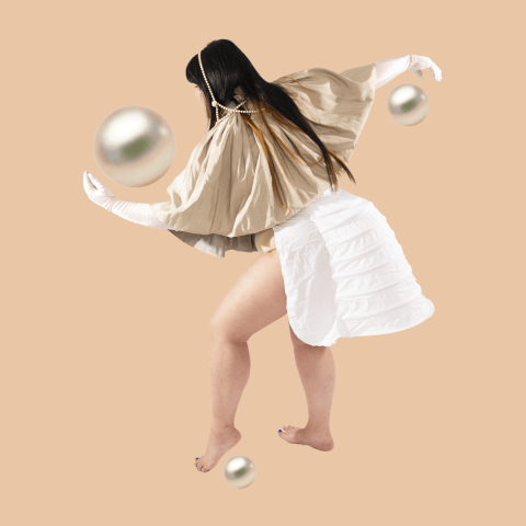 In front of a tan colored background a long haired person wearing a golden top stretches out their arms to the front and back. Three pearls of great size are shown by their hands and left foot.