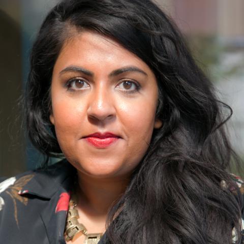 A woman with long dark hair and a black shirt with red flowers