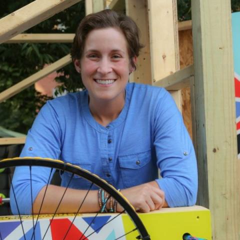 Amy leans over a wooded structure with shapes painted on it