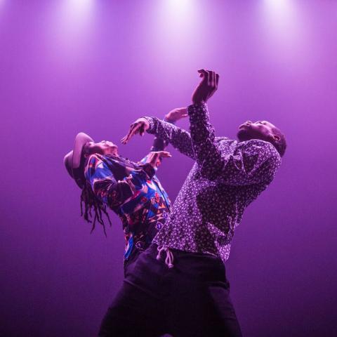 Jon Boogz and Lil Buck throw their arms up on a stage with purple lights