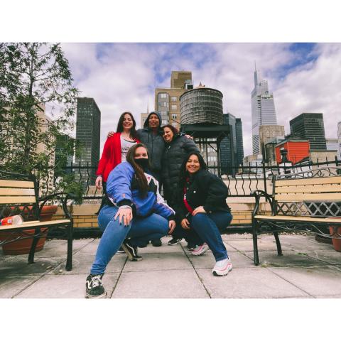 In casual attire, five folks pose in front of a water tower.