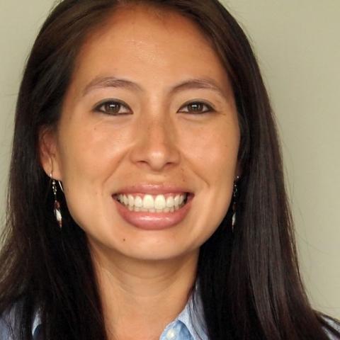 Woman with earrings smiles wide.