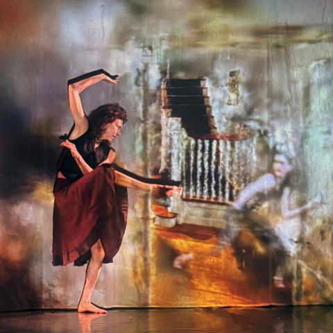 A performer in a red skirt and black top strikes a post.