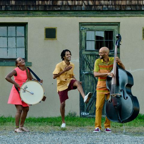 In front of an old ranch home, five musicians play and dance.