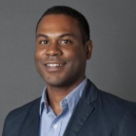 Man in a suit smiles in a studio space