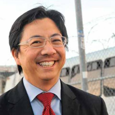 Man in a tie smiles on a street corner